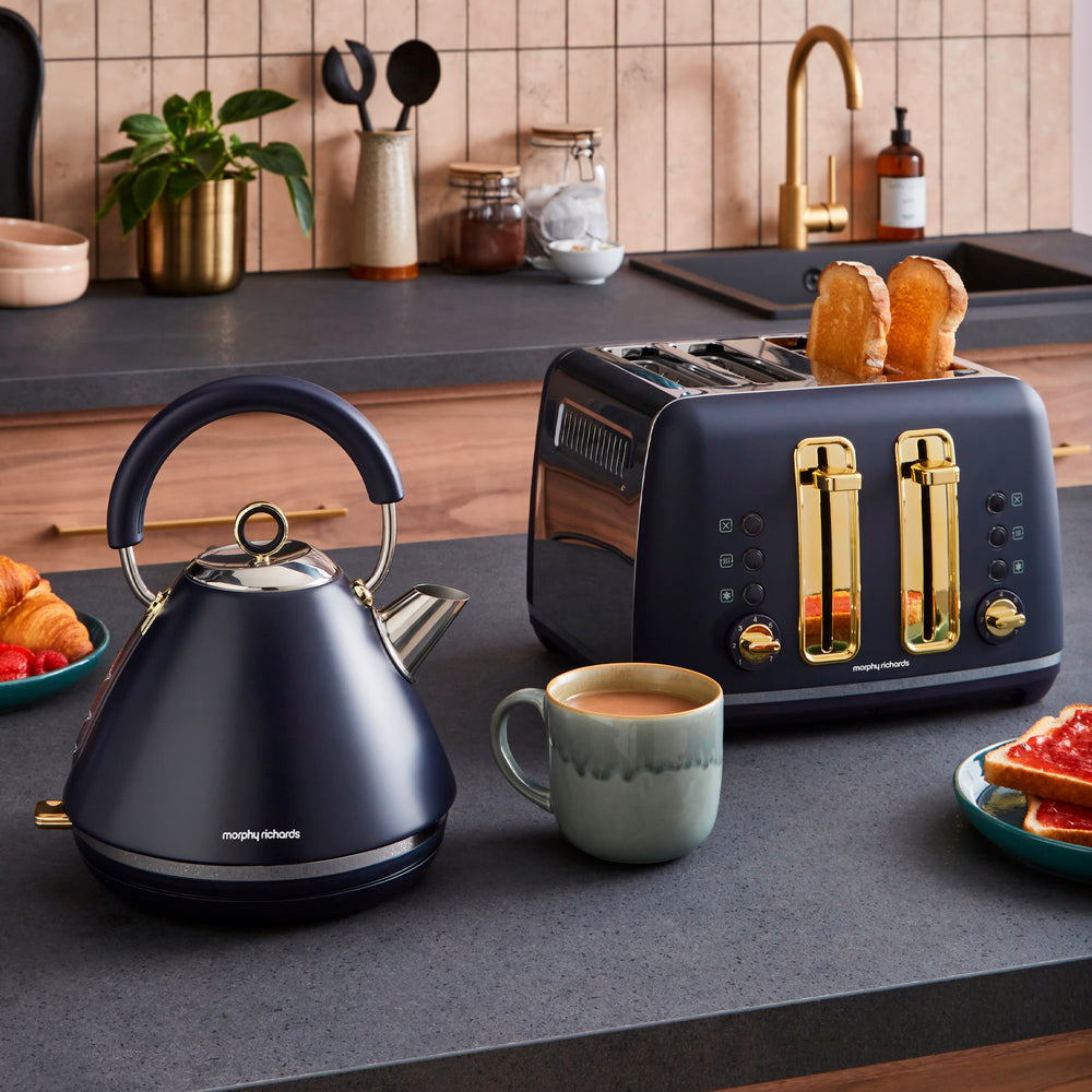 Kitchen counter with a blue kettle, toaster, and coffee cup on a wooden kitchen background.