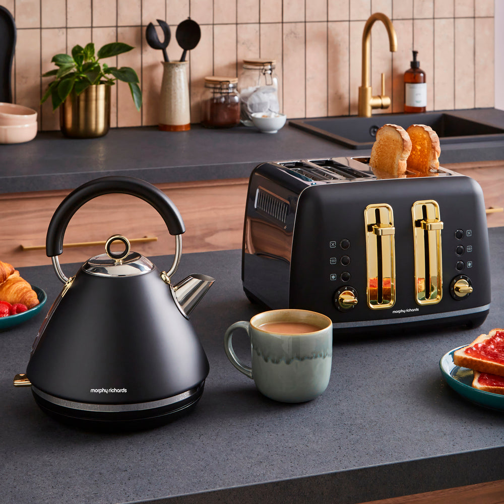 Black kettle and toaster on a kitchen counter with a cup of coffee and toast.
