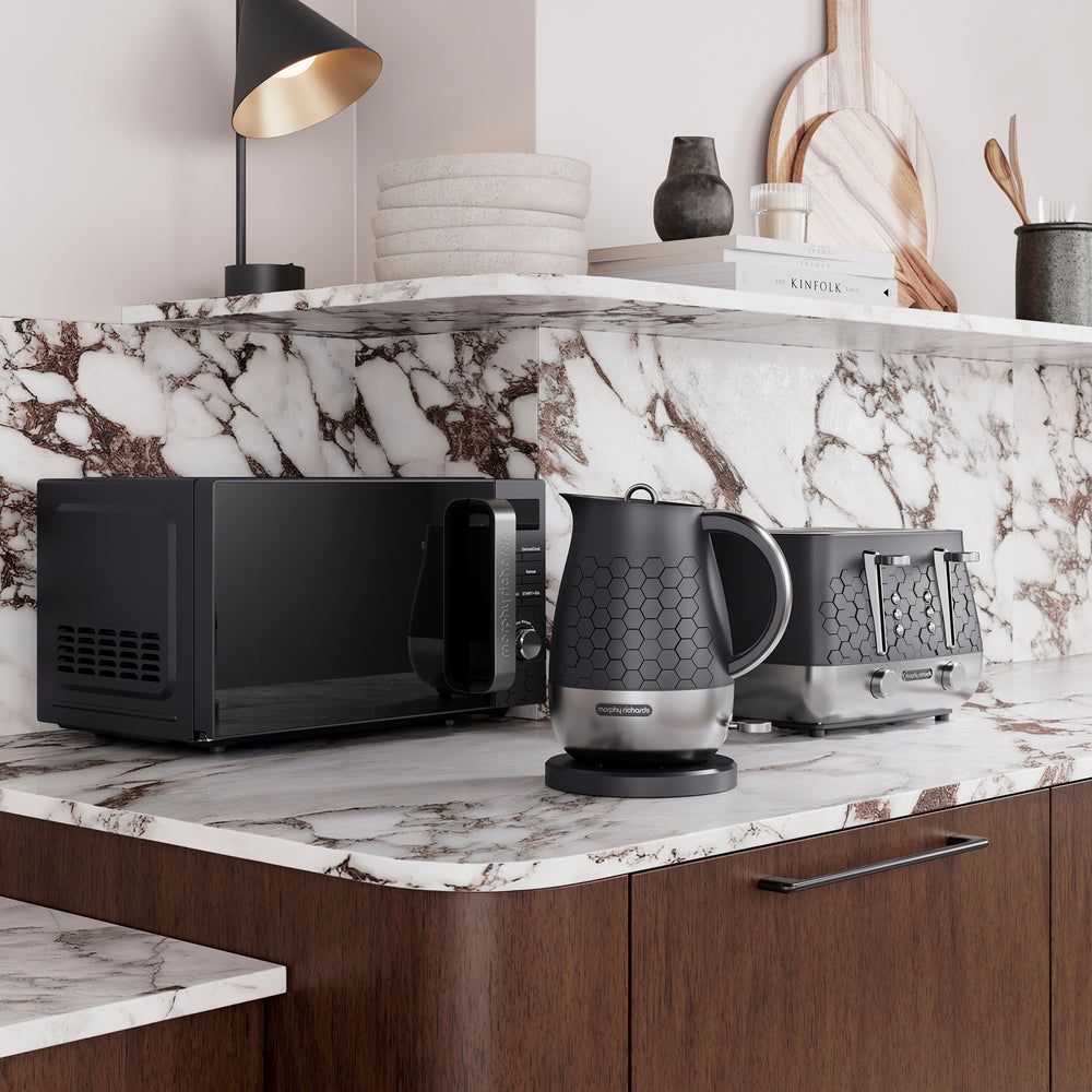 Modern kitchen counter with Morphy Richards Cassini black microwave, kettle, and toaster on a marble countertop.