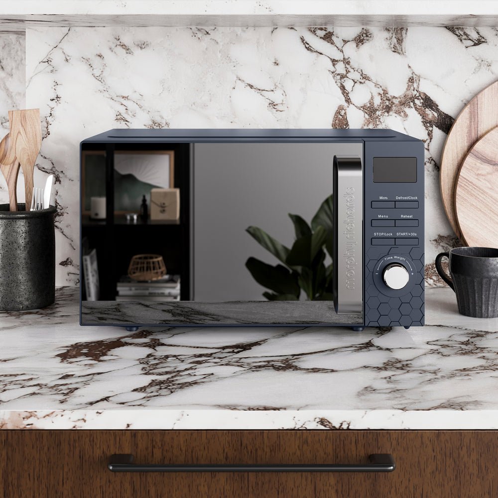 Navy microwave oven on a marble countertop with a kitchen setting.