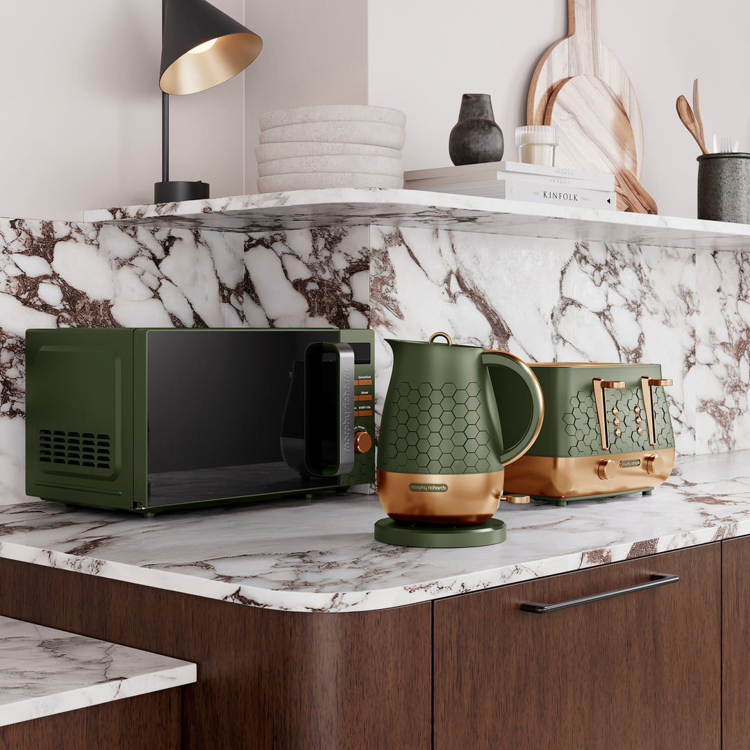 Green microwave, kettle, and toaster on a marble countertop with a shelf in the background.