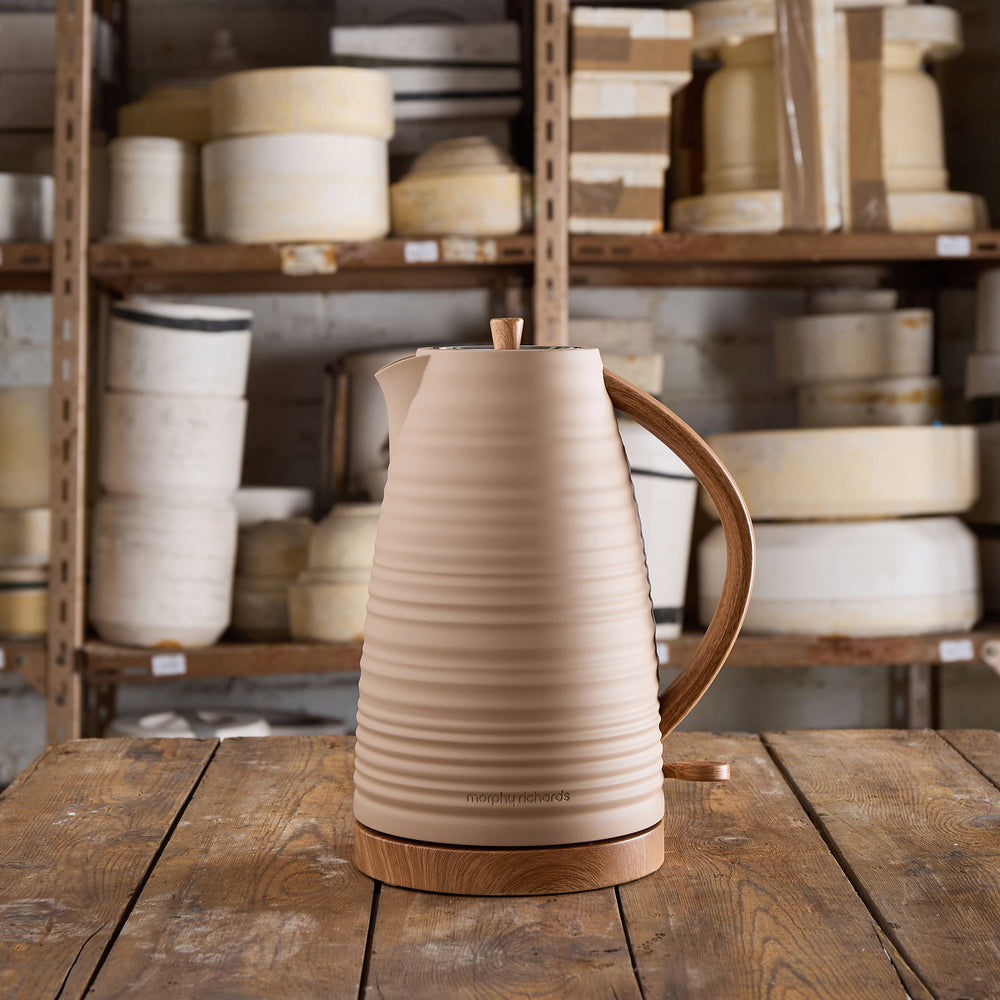 Beige electric kettle with wooden handle on a wooden table in a warehouse setting