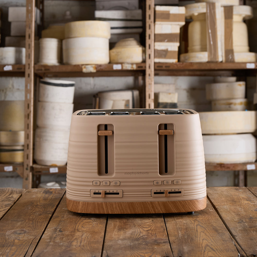 Beige toaster on a wooden table with shelves of white pottery in the background