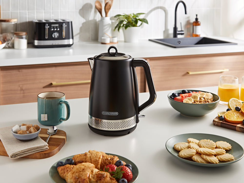Black electric kettle on a kitchen counter with food and drinks