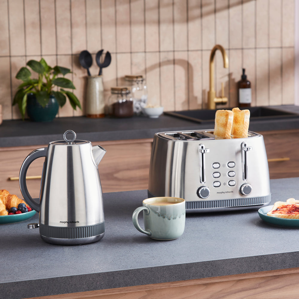 Kitchen counter with a silver kettle, toaster, and mug, with a blurred kitchen background.